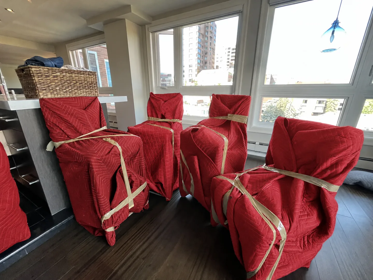 Chairs secured in red protective moving blankets inside a home