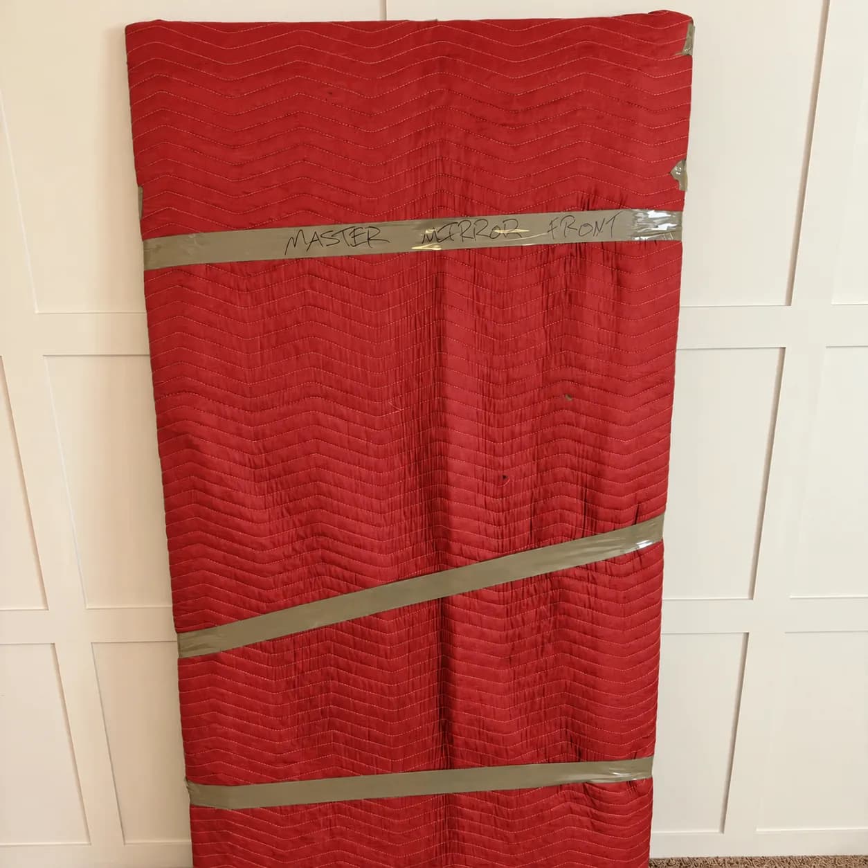 A mirror secured in red quilted protective wrapping
